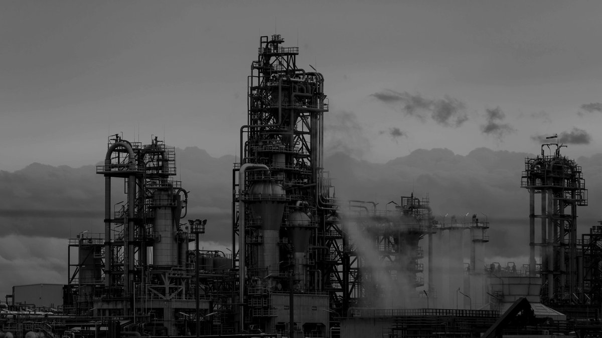 Industrial refinery structures and pipework at dusk; illustrative stock photograph.